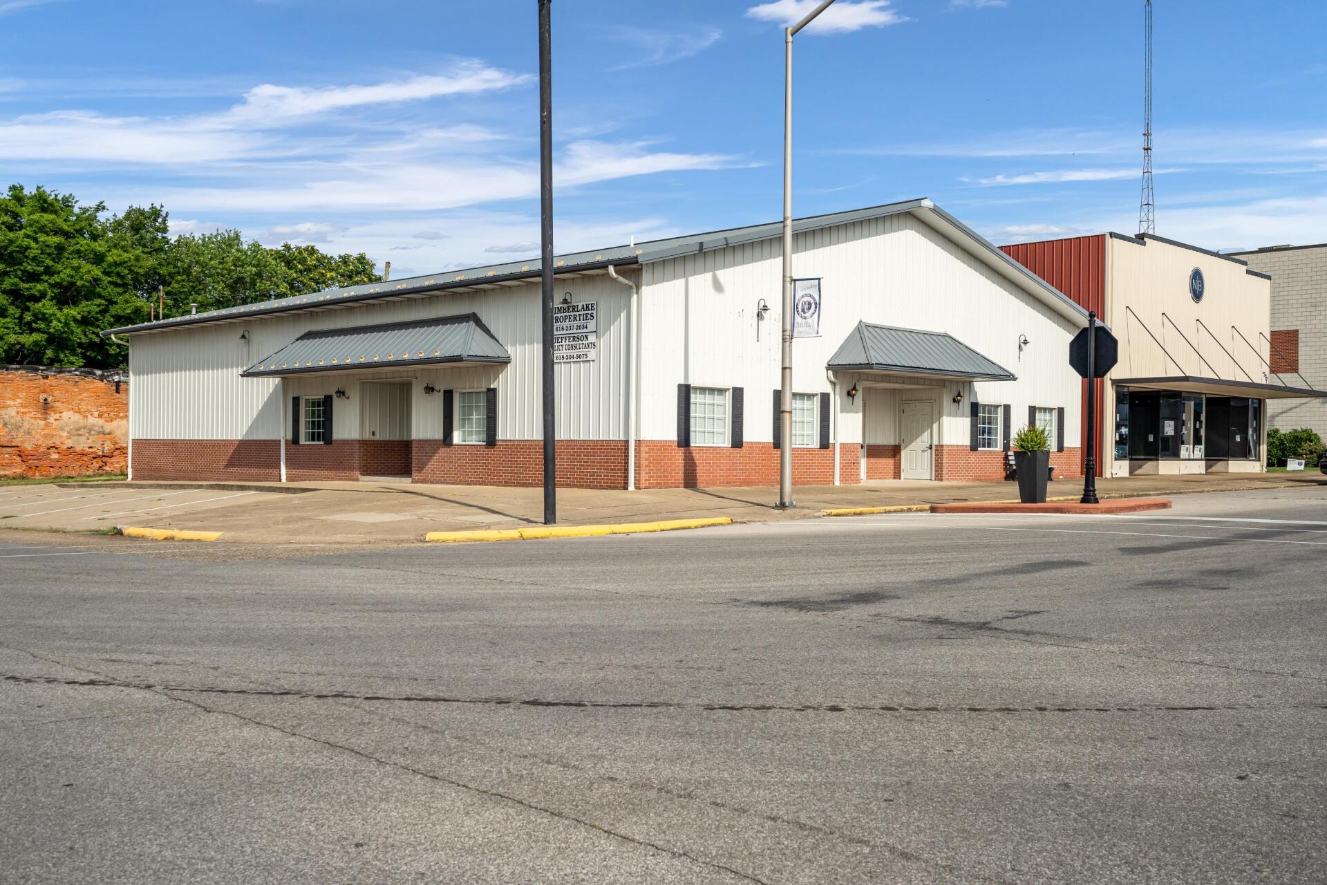 A large white building is sitting on the corner of a street.