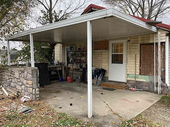 A small house with a covered porch and a red roof.
