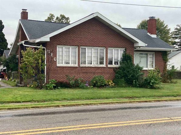 A brick house with a black roof is sitting on the side of the road.