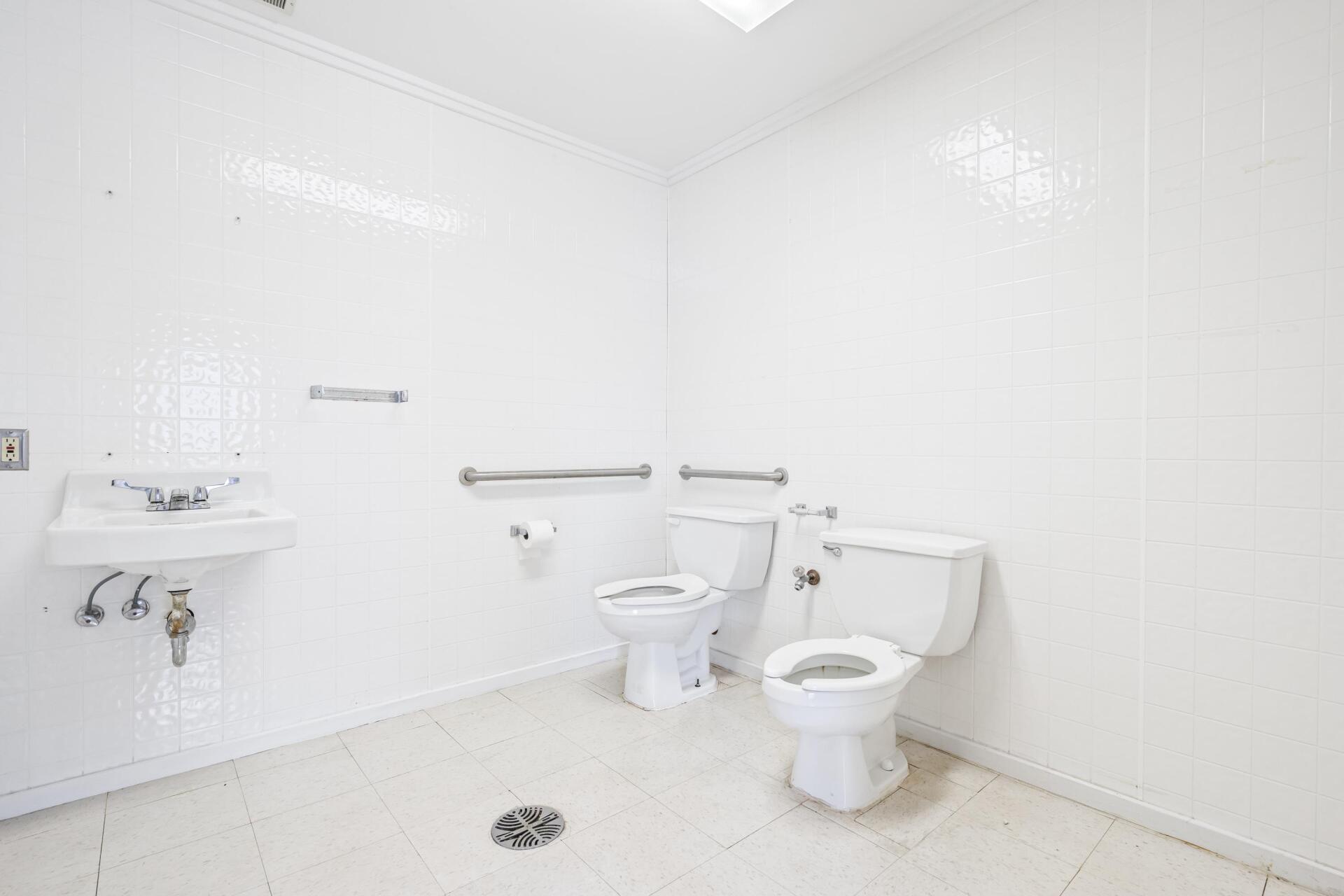 A bathroom with two toilets and a sink.