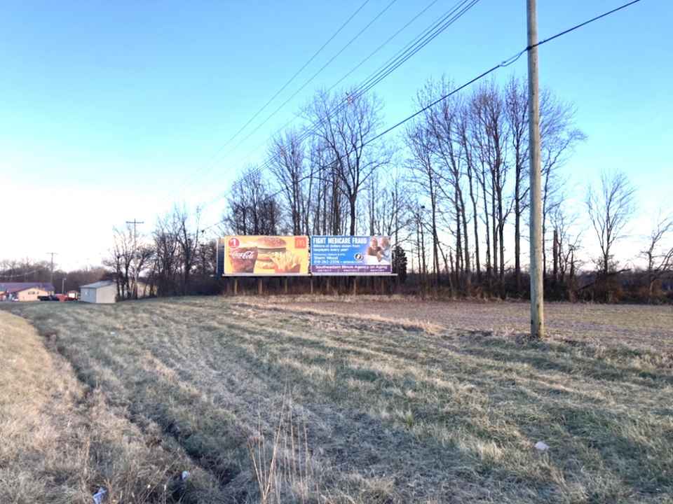 A large billboard is sitting in the middle of a field.