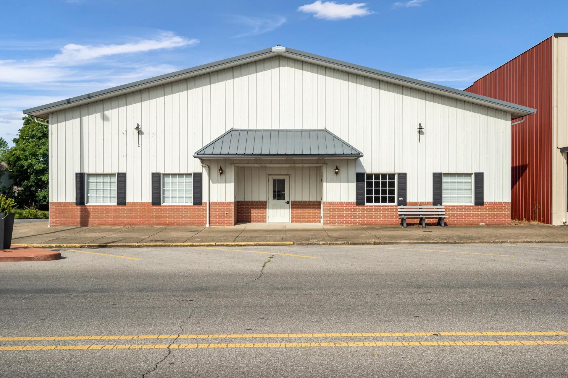 A large white building with a brick facade is sitting on the side of the road.