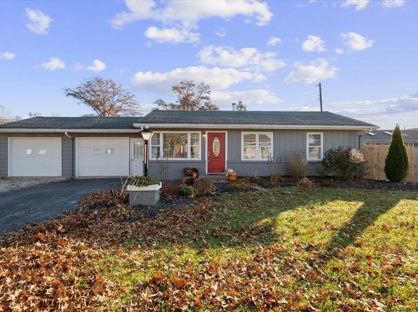 A gray house with a red door and two garages