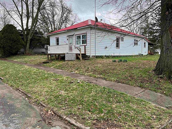 A small white house with a red roof is for sale.