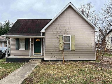 A small house with a porch and a car parked in front of it.