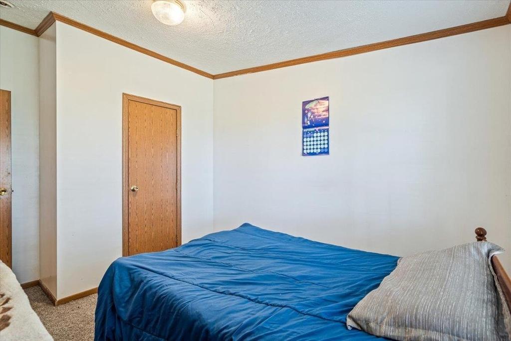 A bedroom with a blue bed and a painting on the wall.