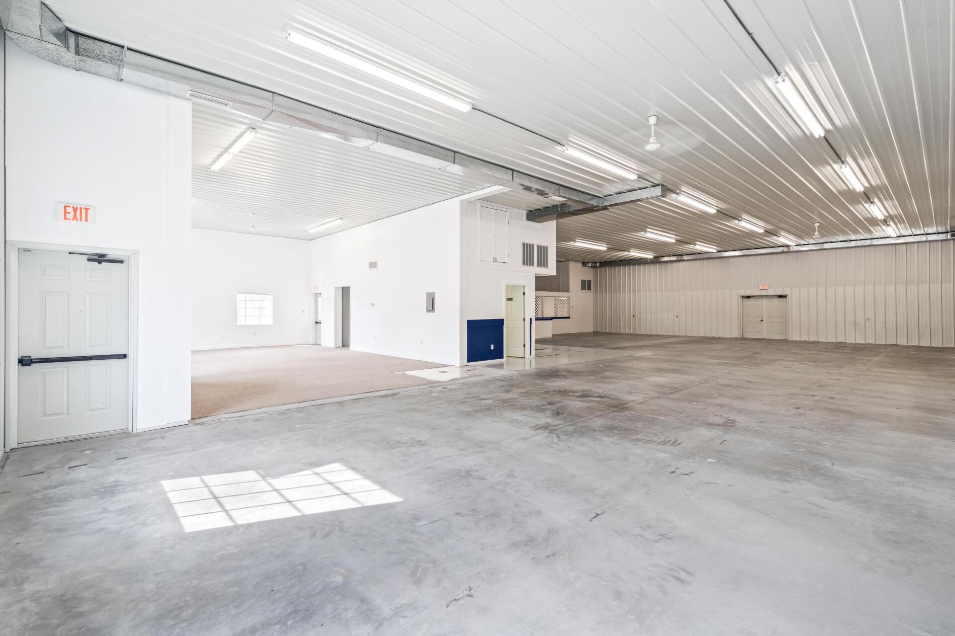 A large empty warehouse with white walls and a concrete floor.