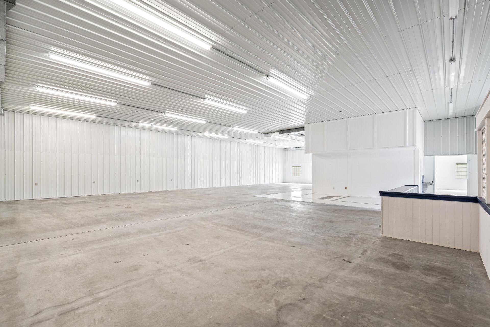 A large empty warehouse with white walls and a concrete floor.
