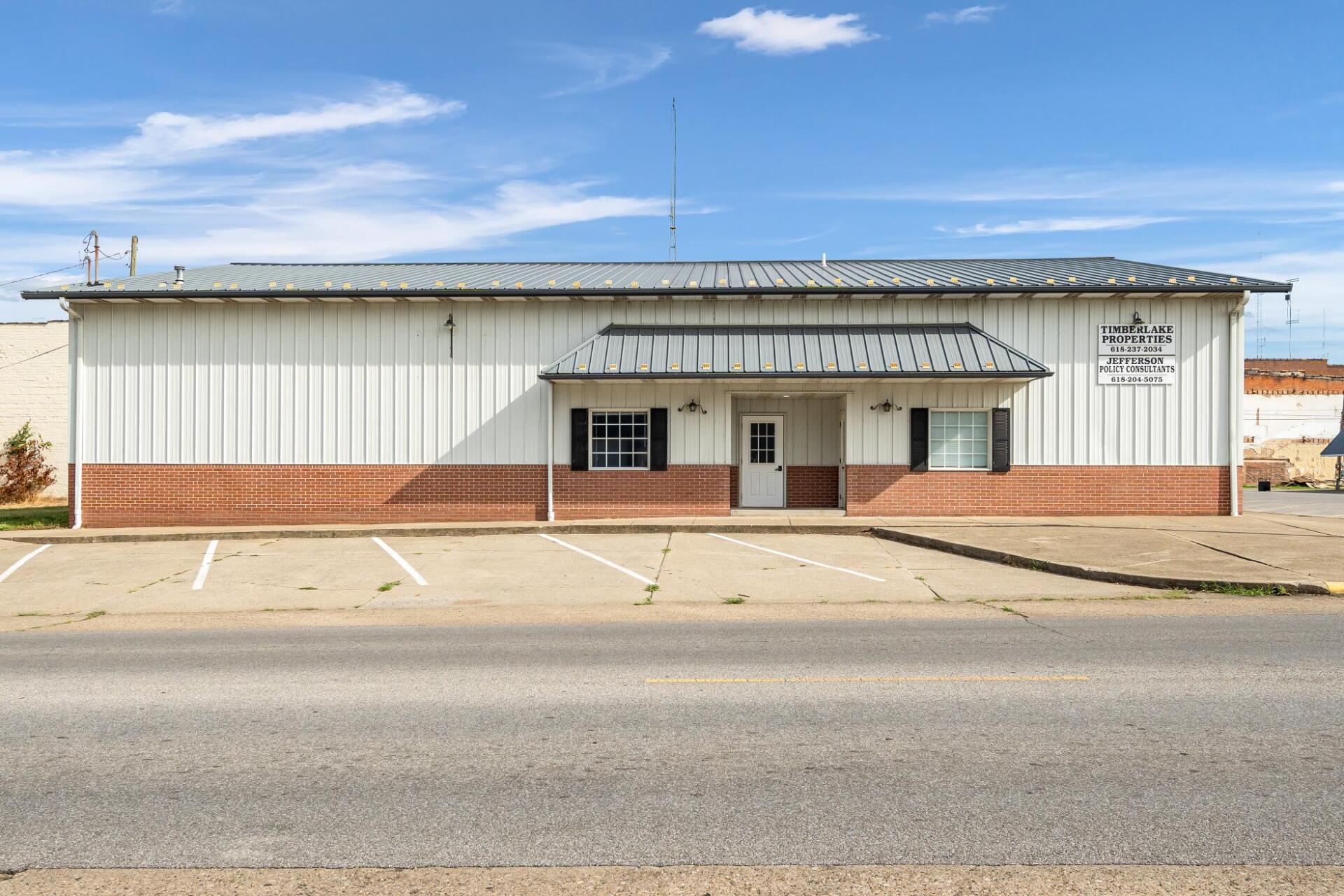 A large white building with a brick facade and a parking lot in front of it.
