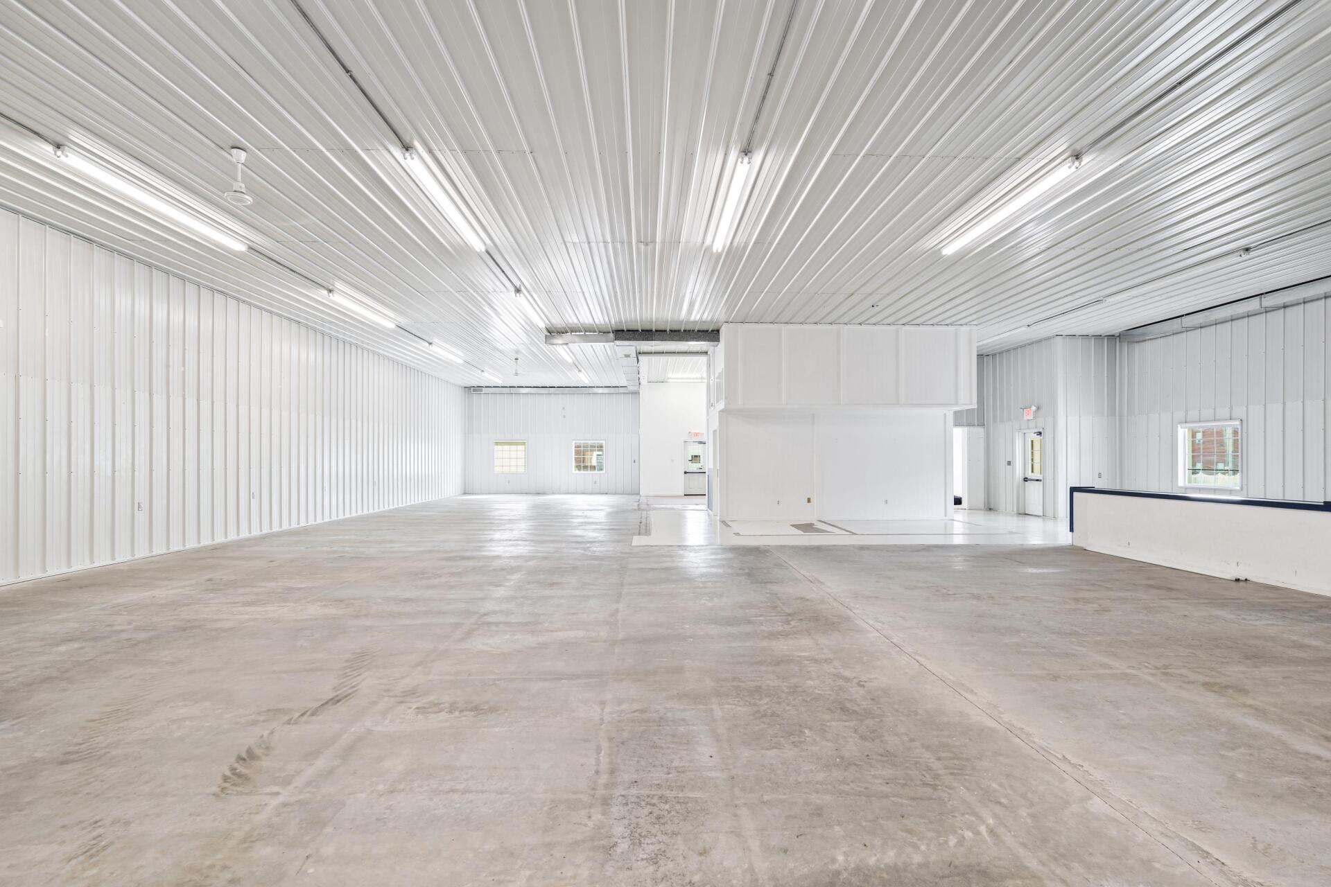 A large empty warehouse with white walls and a concrete floor.