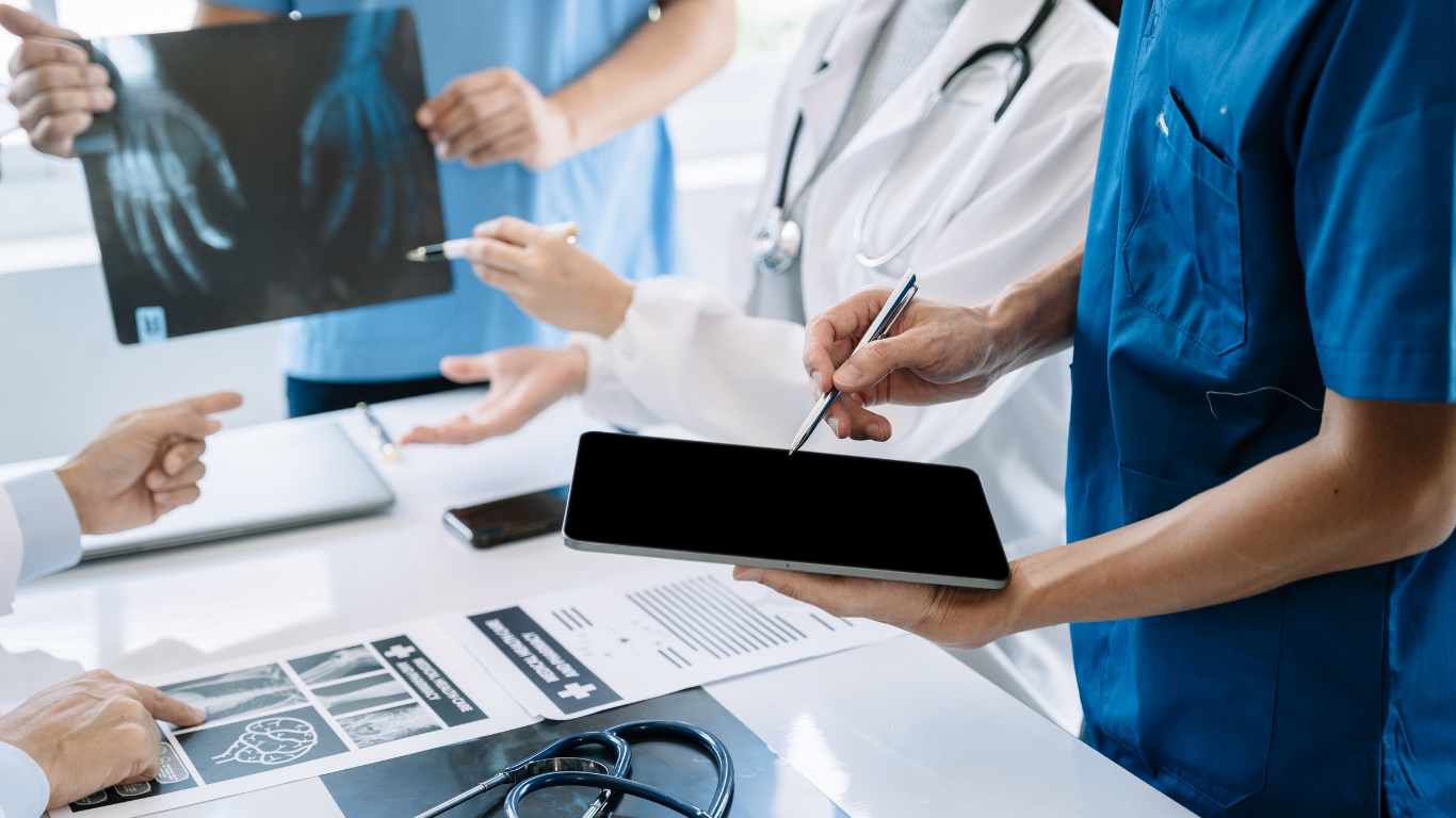 A group of doctors are sitting around a table looking at an x-ray.