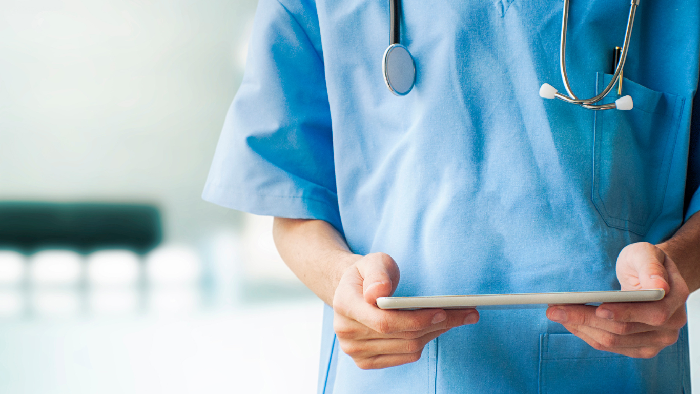A doctor is holding a tablet in his hands.