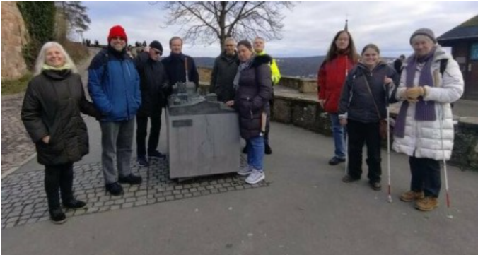Eine Gruppe von Menschen steht nebeneinander auf einem Bürgersteig.
