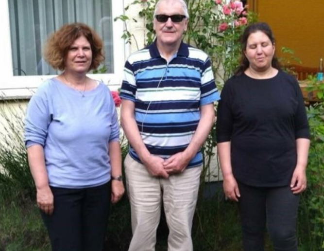 Ein Mann in einem gestreiften Hemd steht zwischen zwei Frauen