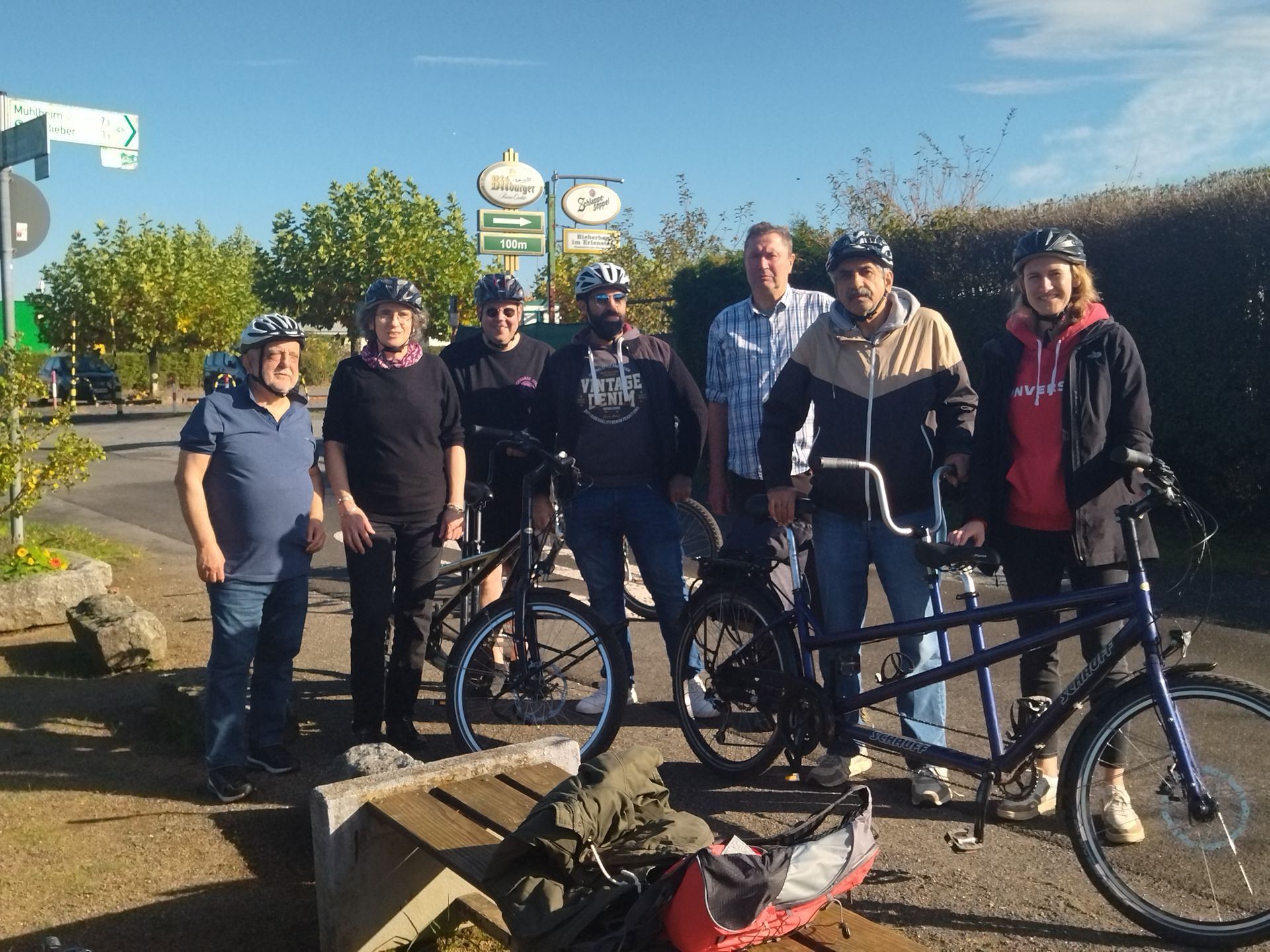 Eine Gruppe von Menschen steht neben einem Tandemfahrrad.