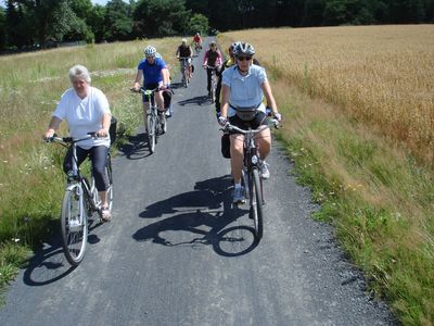 Gruppe von Radfahrern auf einem Schotterweg in ländlicher Gegend bei sonnigem Wetter
