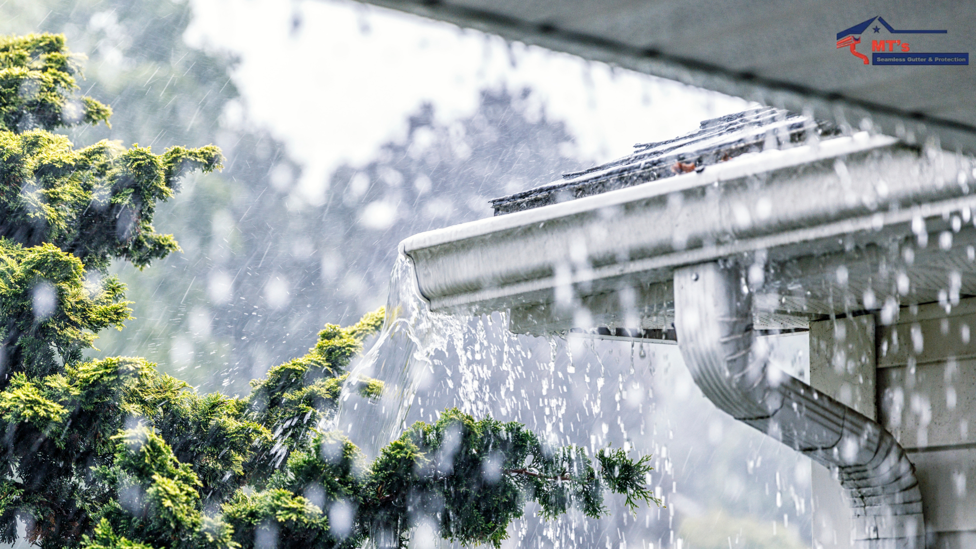 Heavy rain pouring off a residential roof gutter system near green foliage.