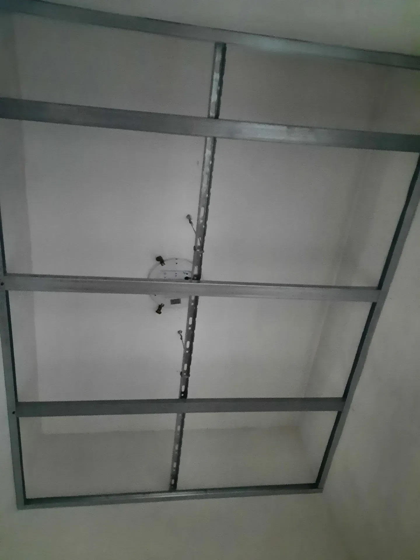 Struttura metallica per controsoffitto, con cavi e lampada a vista.