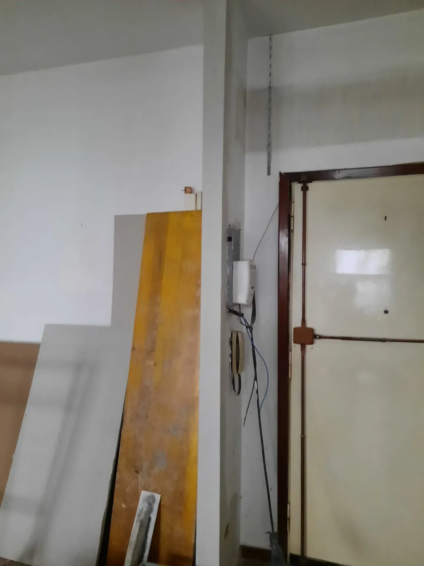 Una porta, una scatola elettrica e un'antenna sono installate su una parete. I materiali da costruzione sono accanto alla parete.