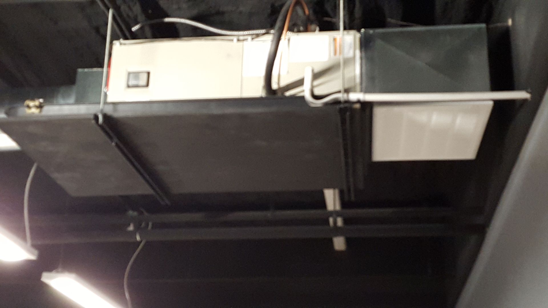 HVAC ductwork and ventilation equipment mounted on a dark industrial ceiling