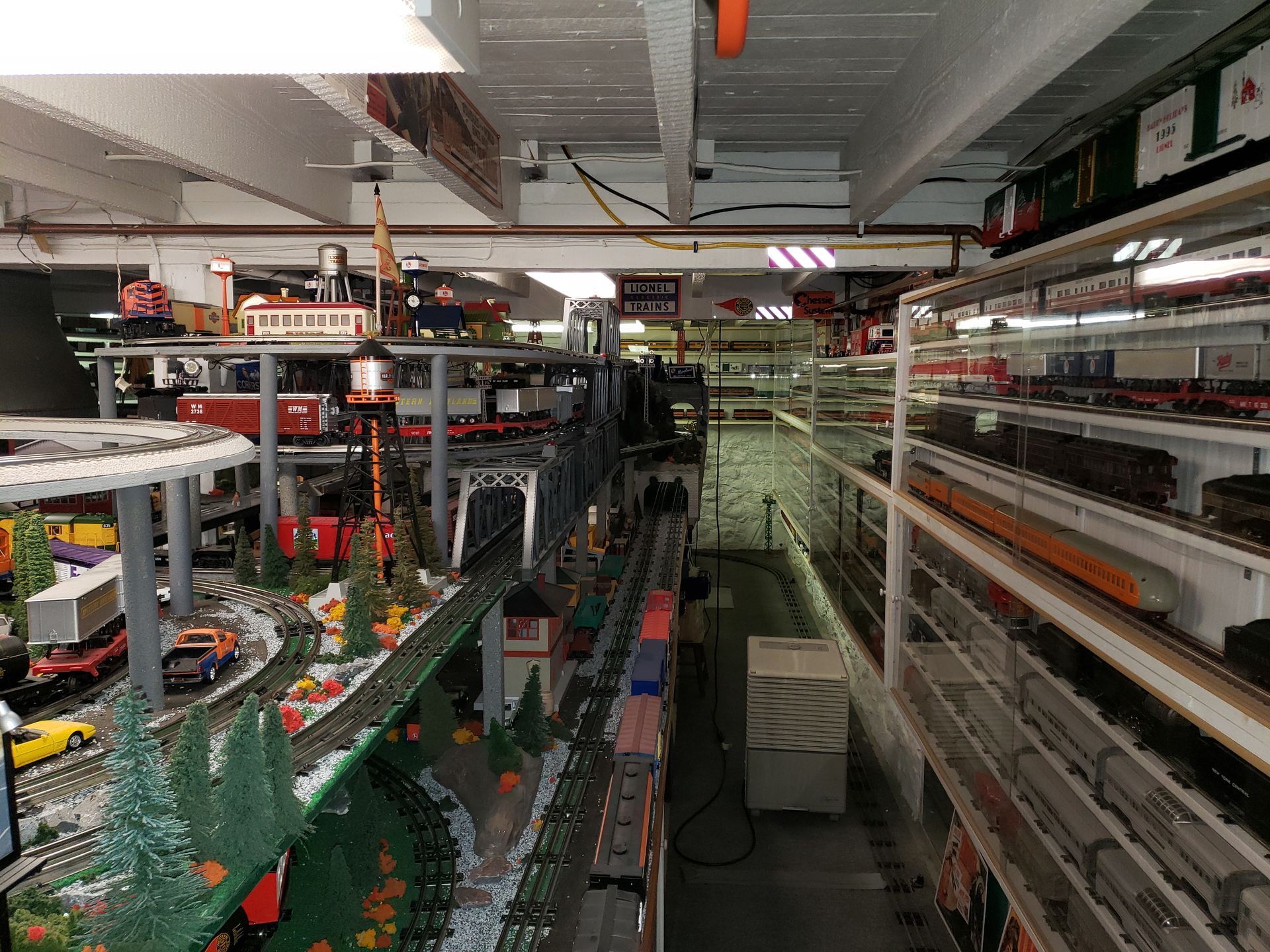 Long factory aisle with conveyor belts, metal racks, and rows of packaged items under bright industrial lights