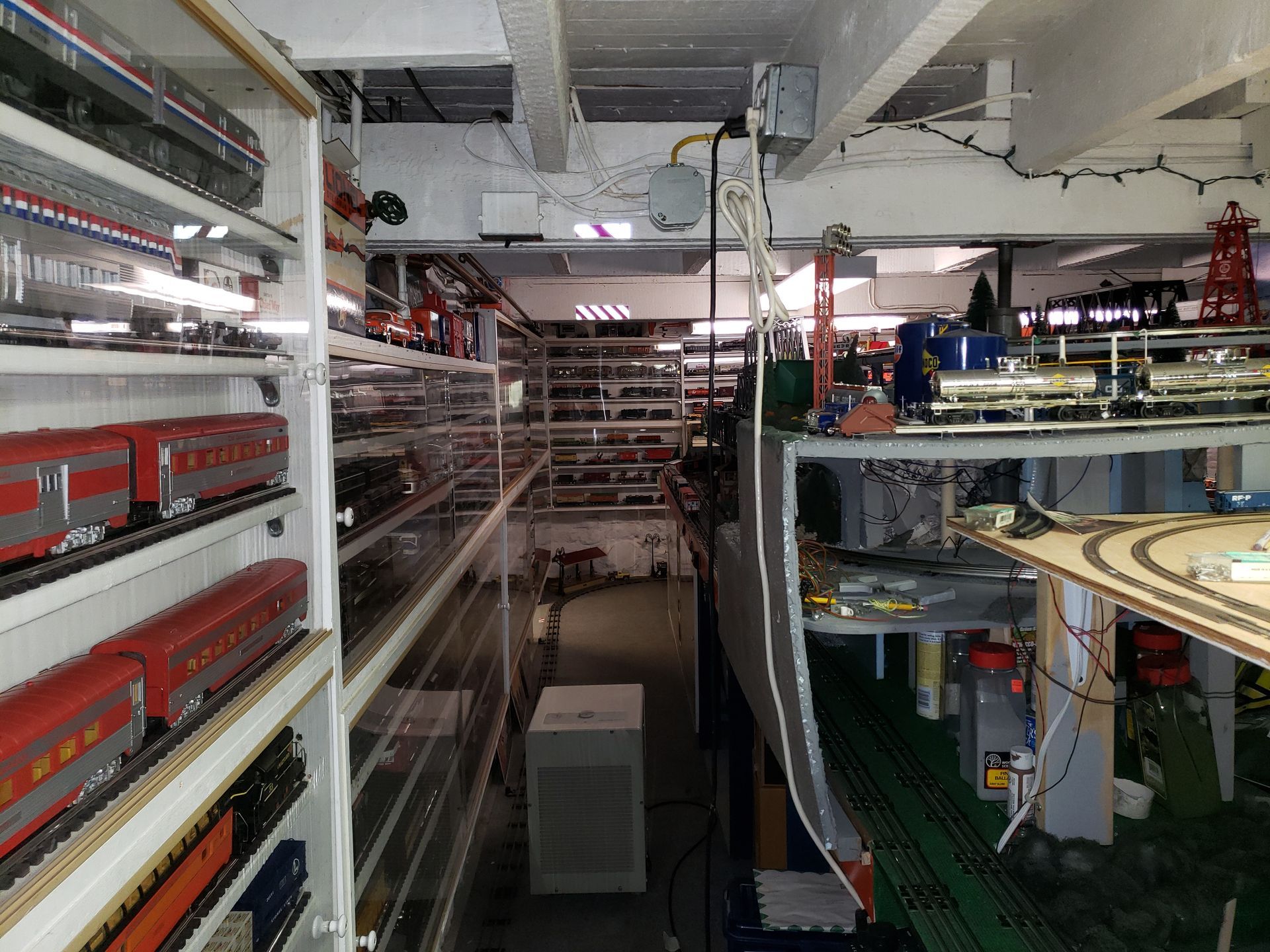 Interior of a train exhibit with model locomotives, tracks, and shelves in a museum-like room