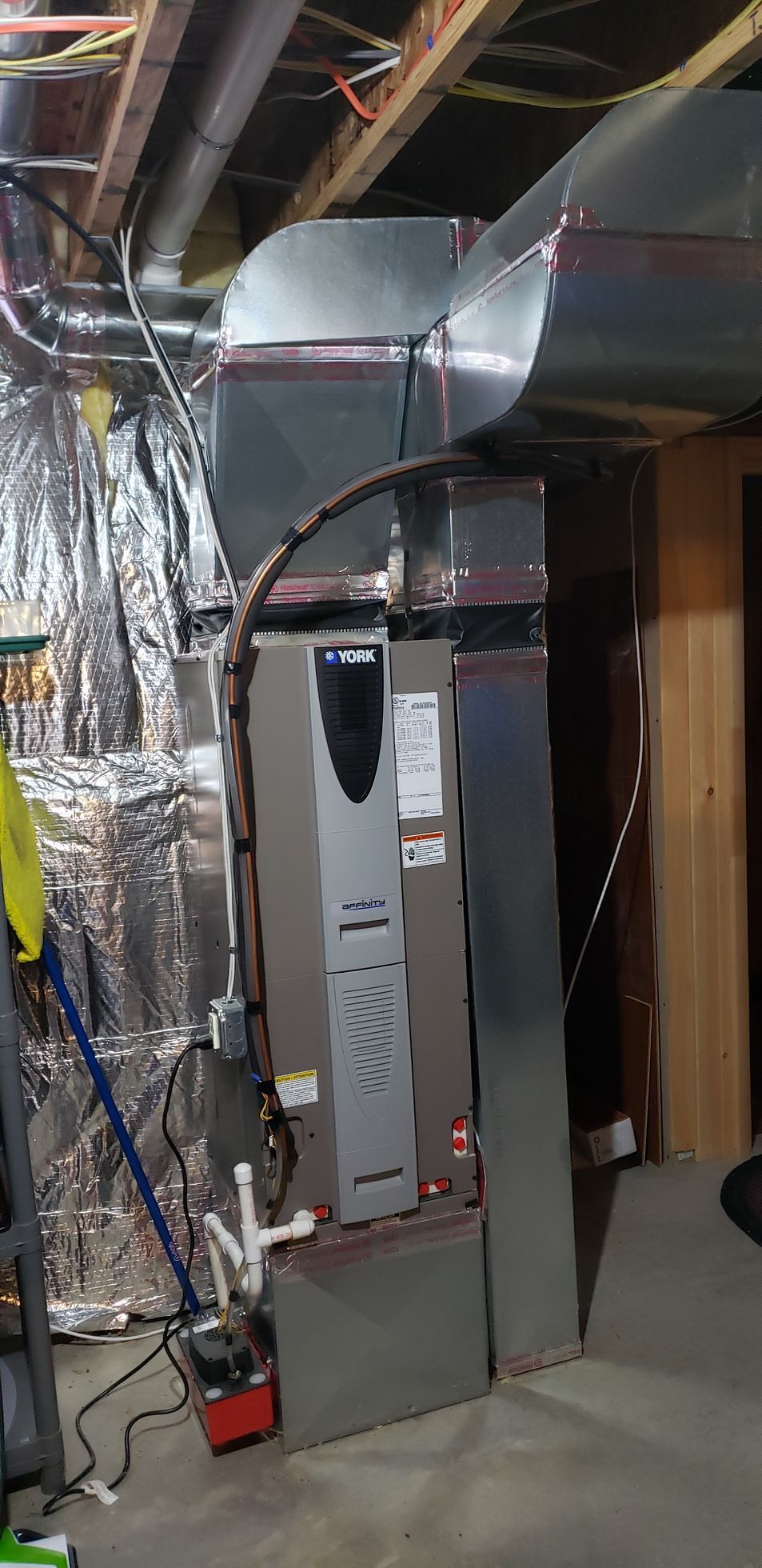 Basement utility room with furnace, ductwork, foil insulation, and exposed framing.