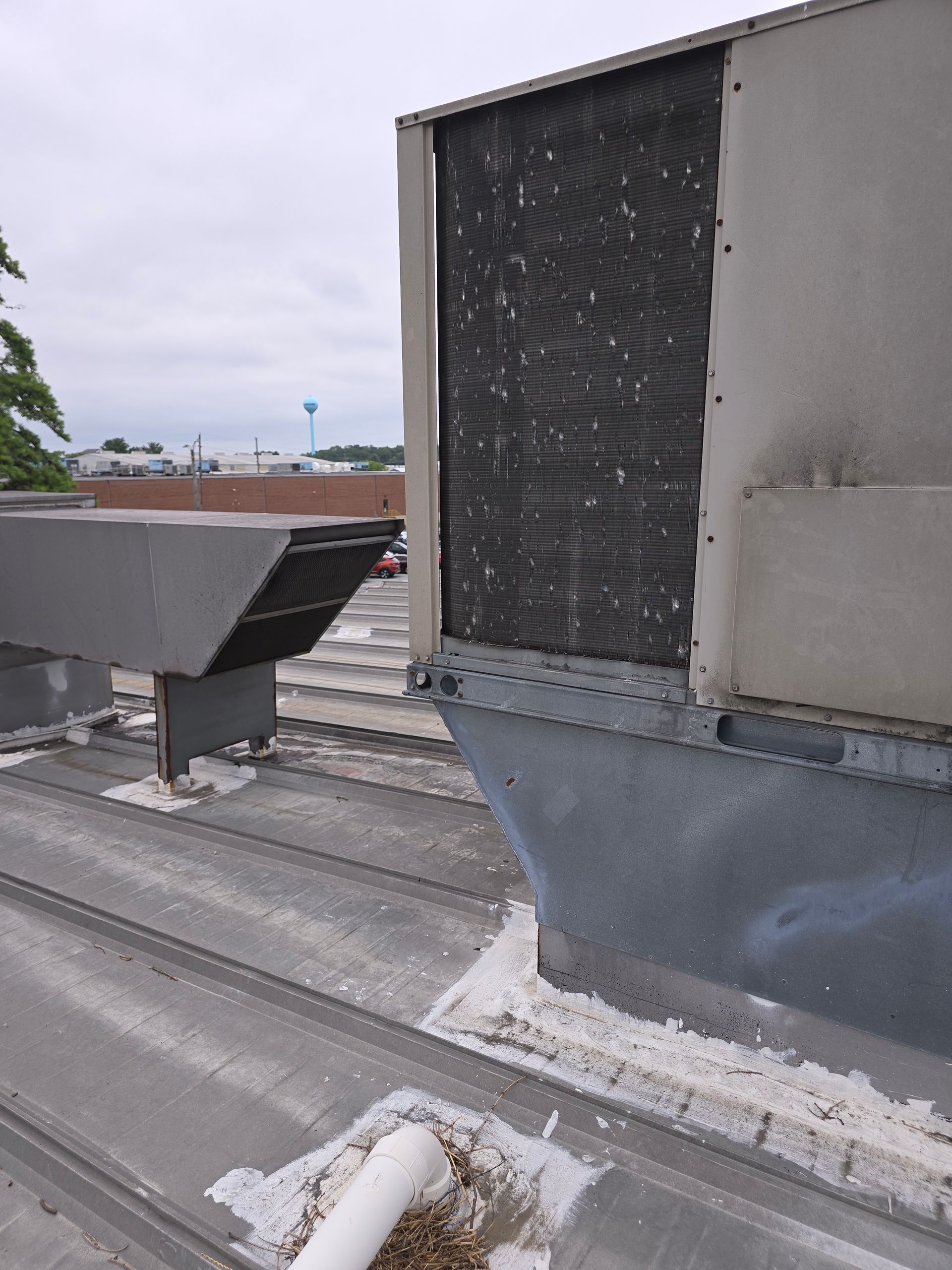 Rooftop HVAC vent and duct on a flat roof under overcast sky