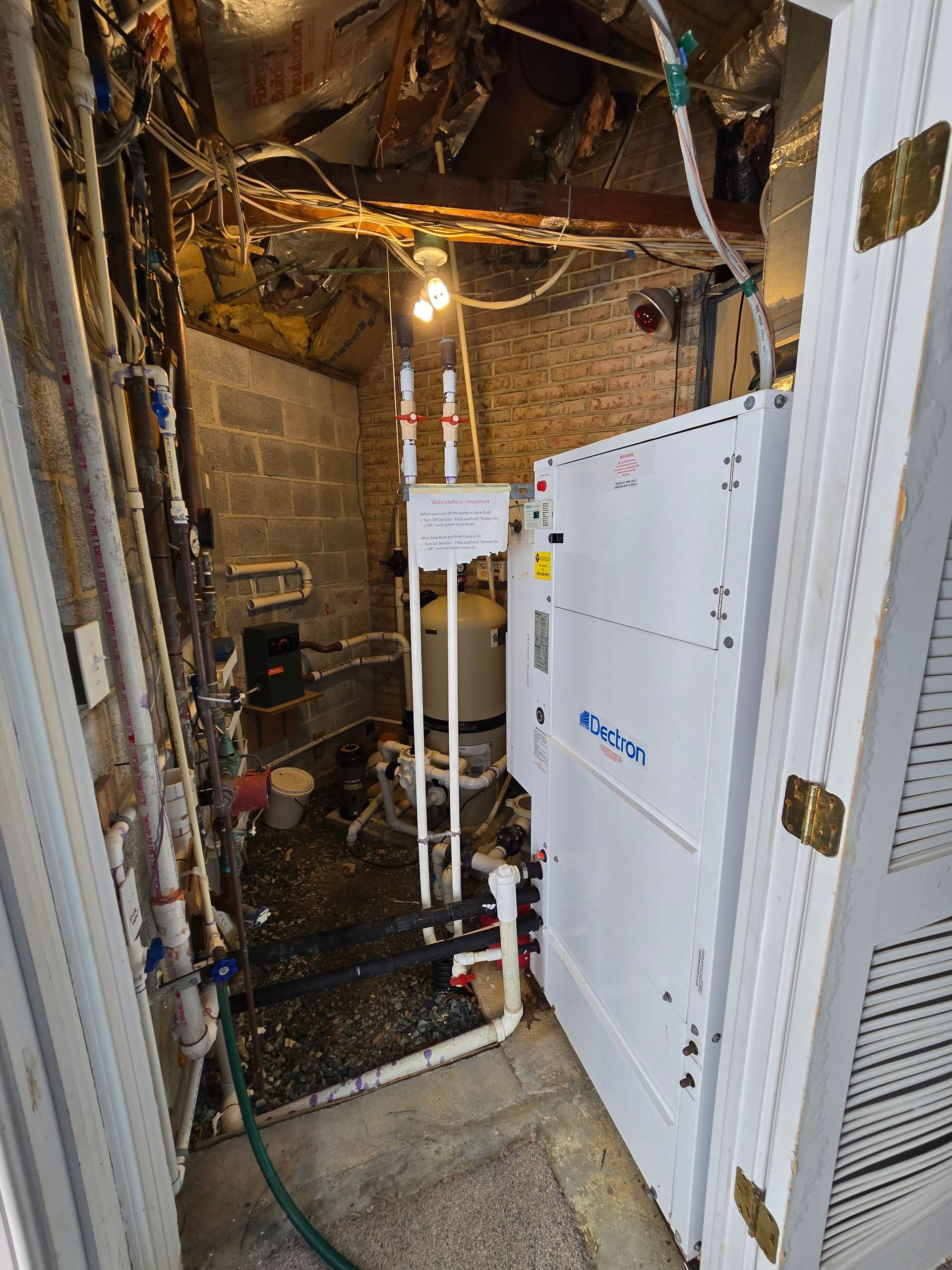 Damaged utility room with exposed pipes, debris, and a white HVAC unit standing amid construction clutter