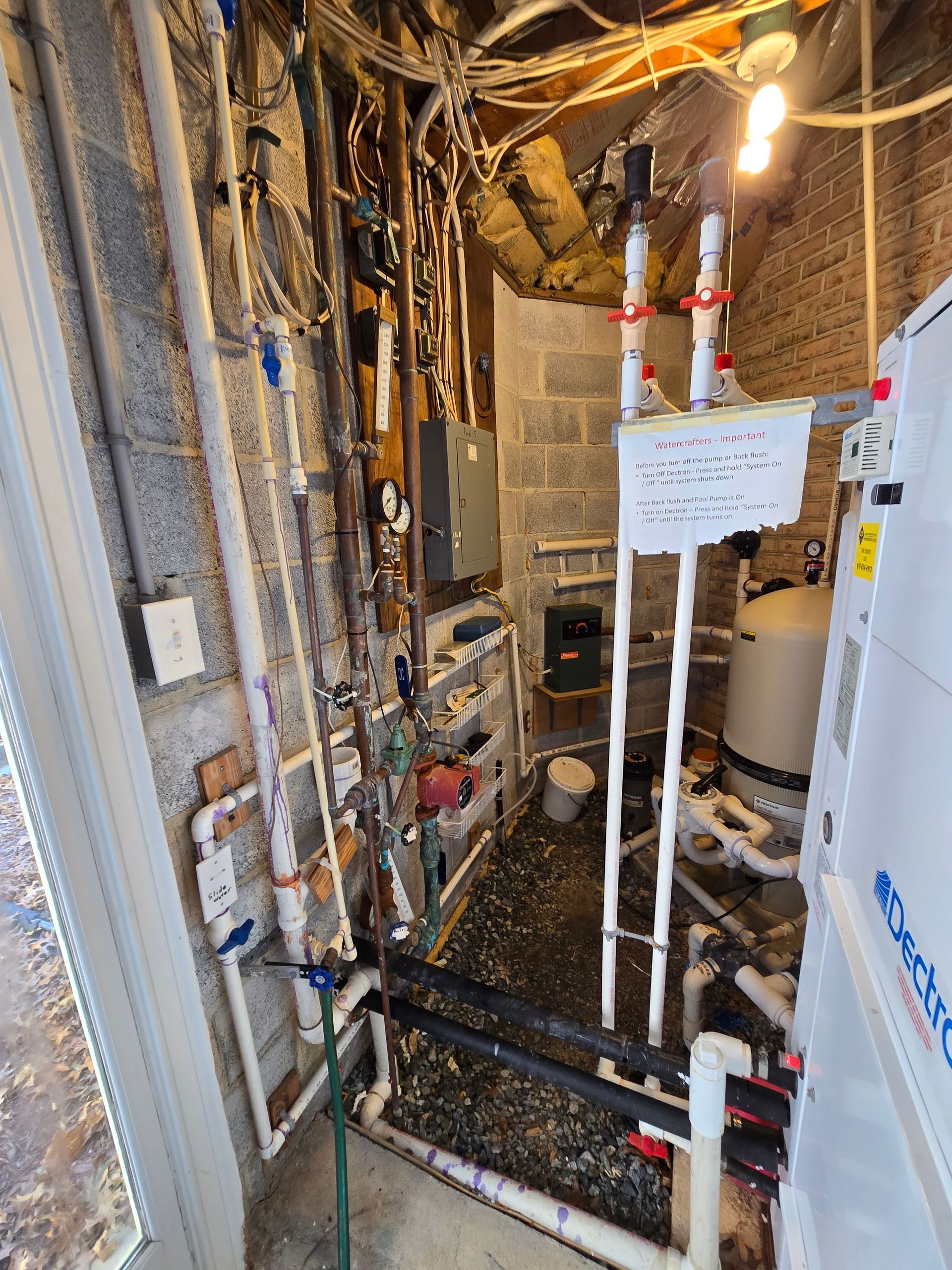 Basement utility area with exposed pipes, wiring, and plumbing in an unfinished wall cavity