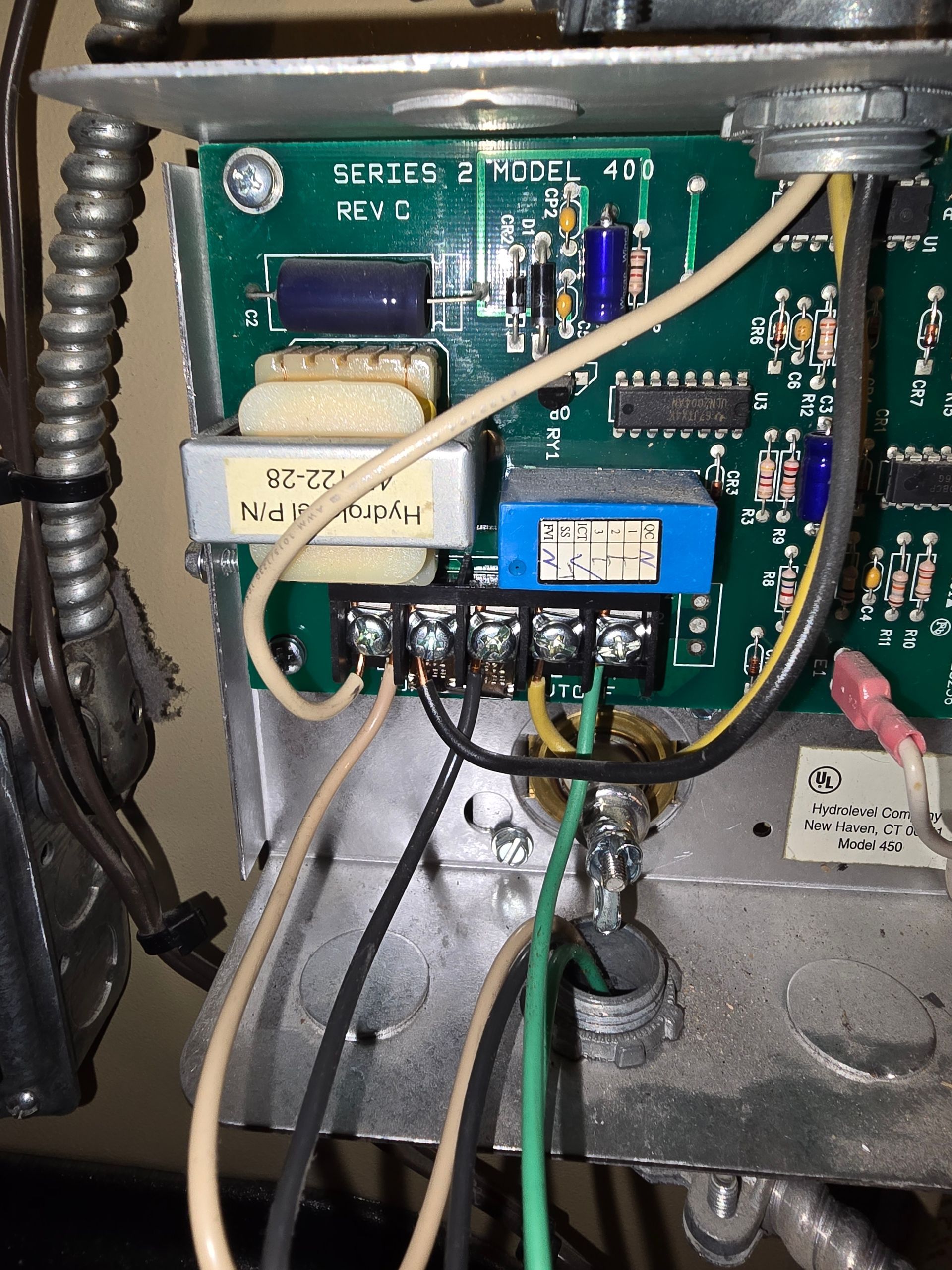 Close-up of an electrical circuit board with wires, connectors, and blue relays inside a metal enclosure