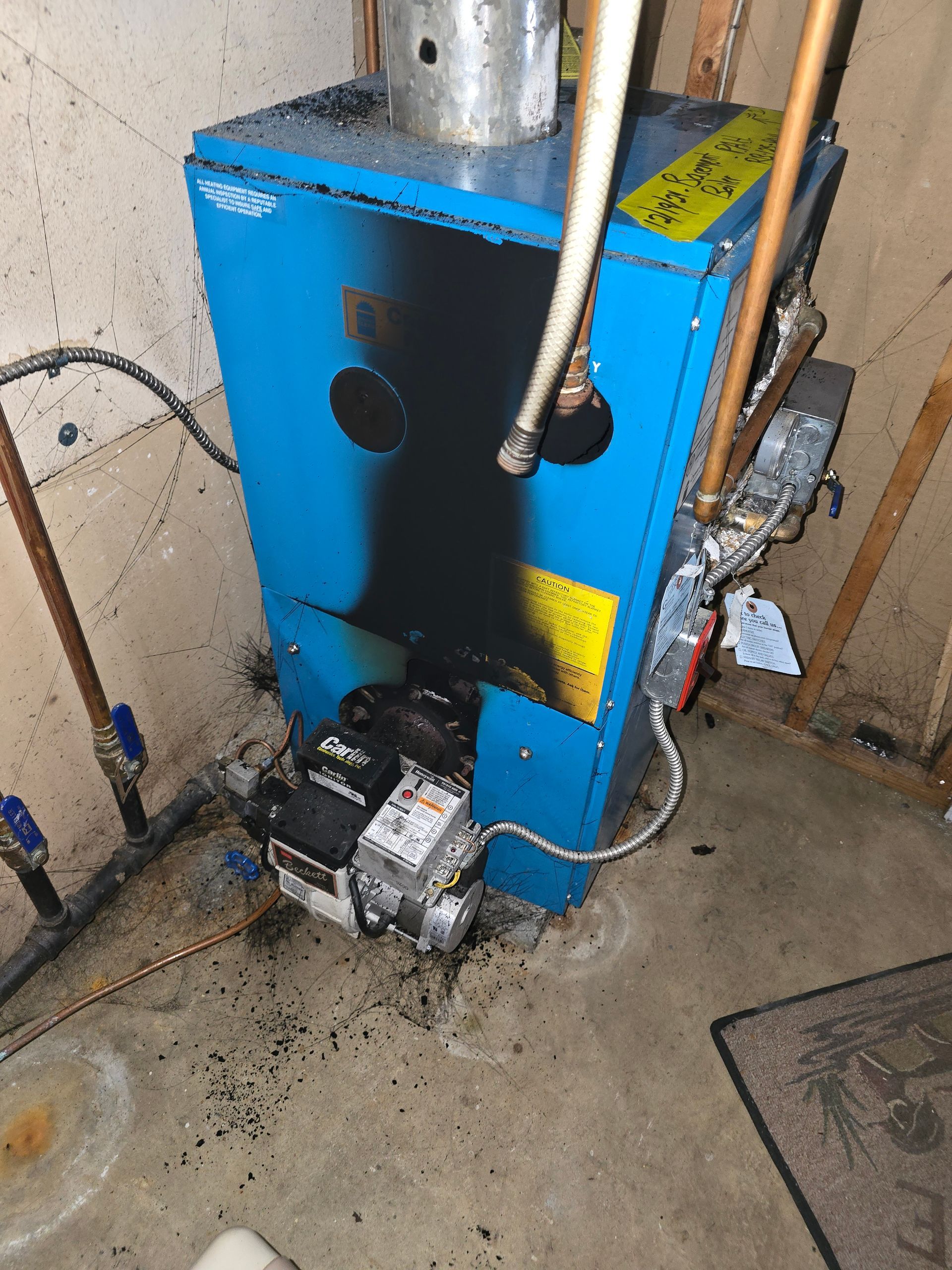 Blue boiler or furnace unit with pipes and a pump in a utility room, viewed from above.