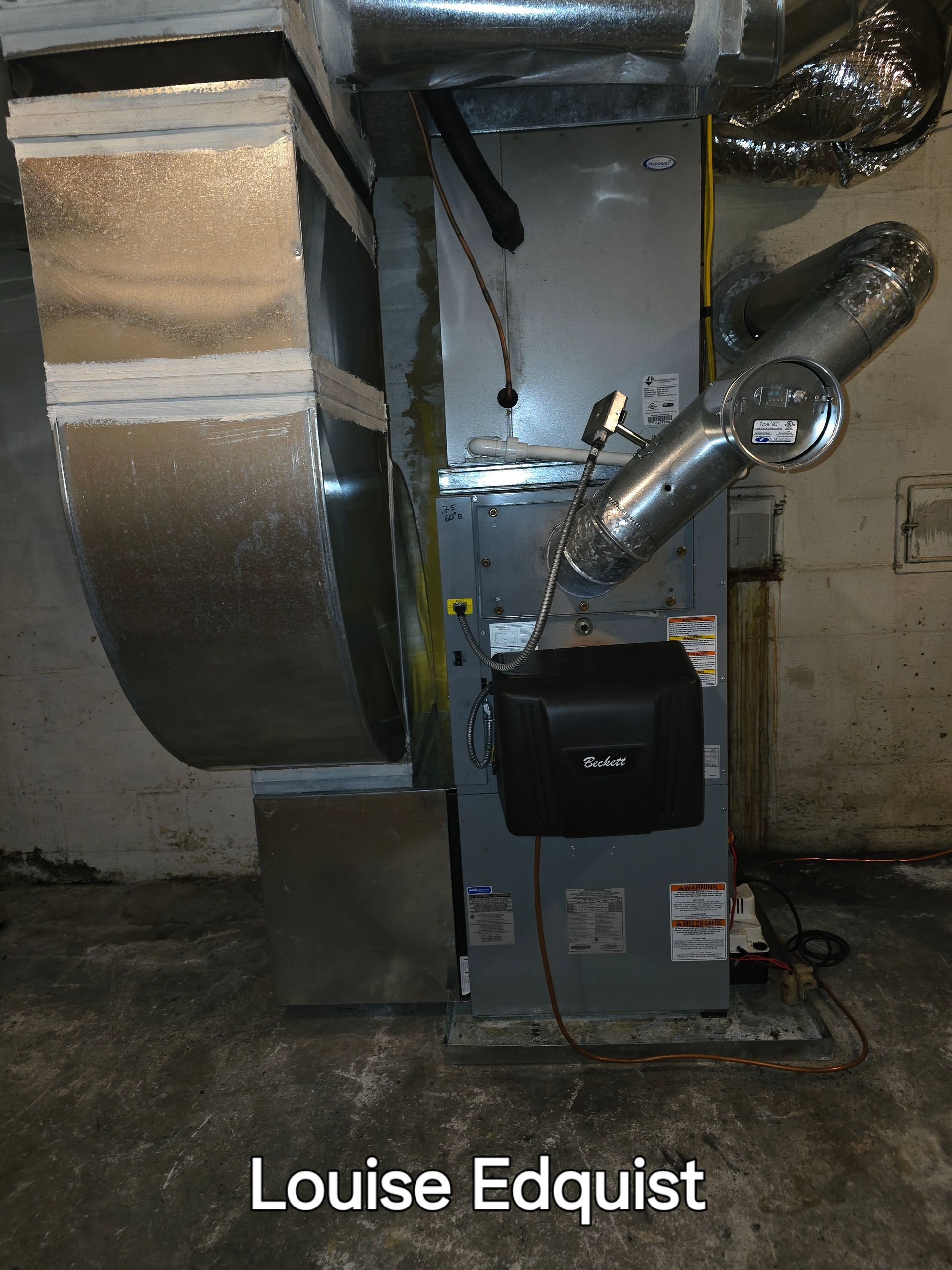 Basement furnace with large silver ductwork and connected metal vent pipes.