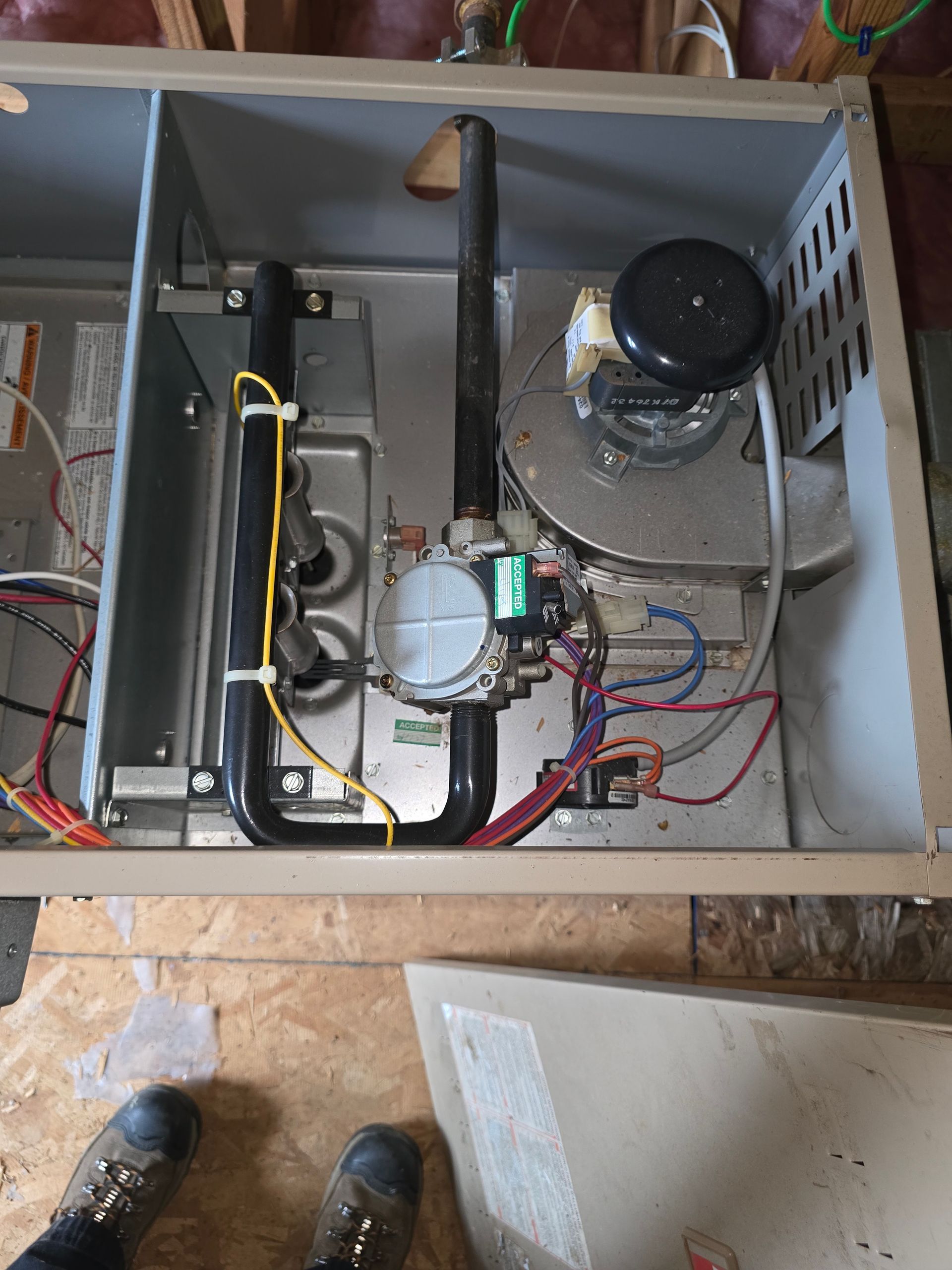 Open electrical control box with wiring, relays, and a black cylindrical component inside a metal enclosure.