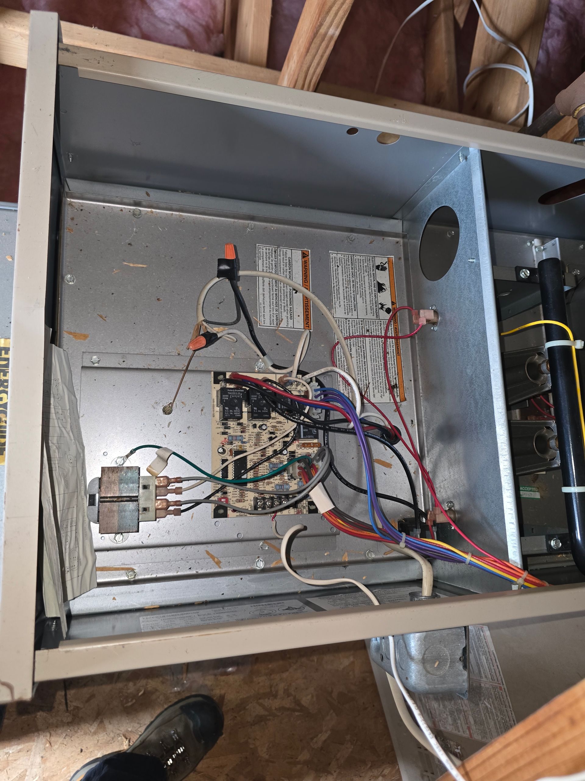 Open electrical panel with exposed wiring, breakers, and metal enclosure inside a wall cavity.