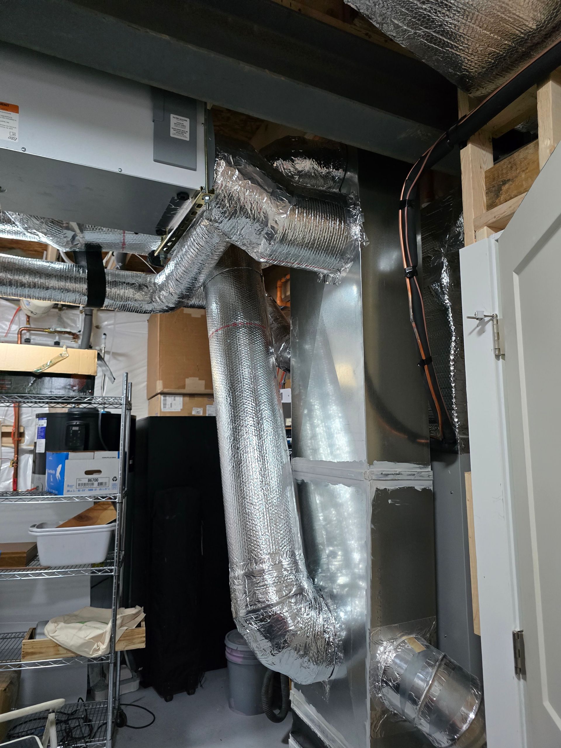 Insulated silver HVAC ducts in an unfinished basement or utility space with exposed framing.