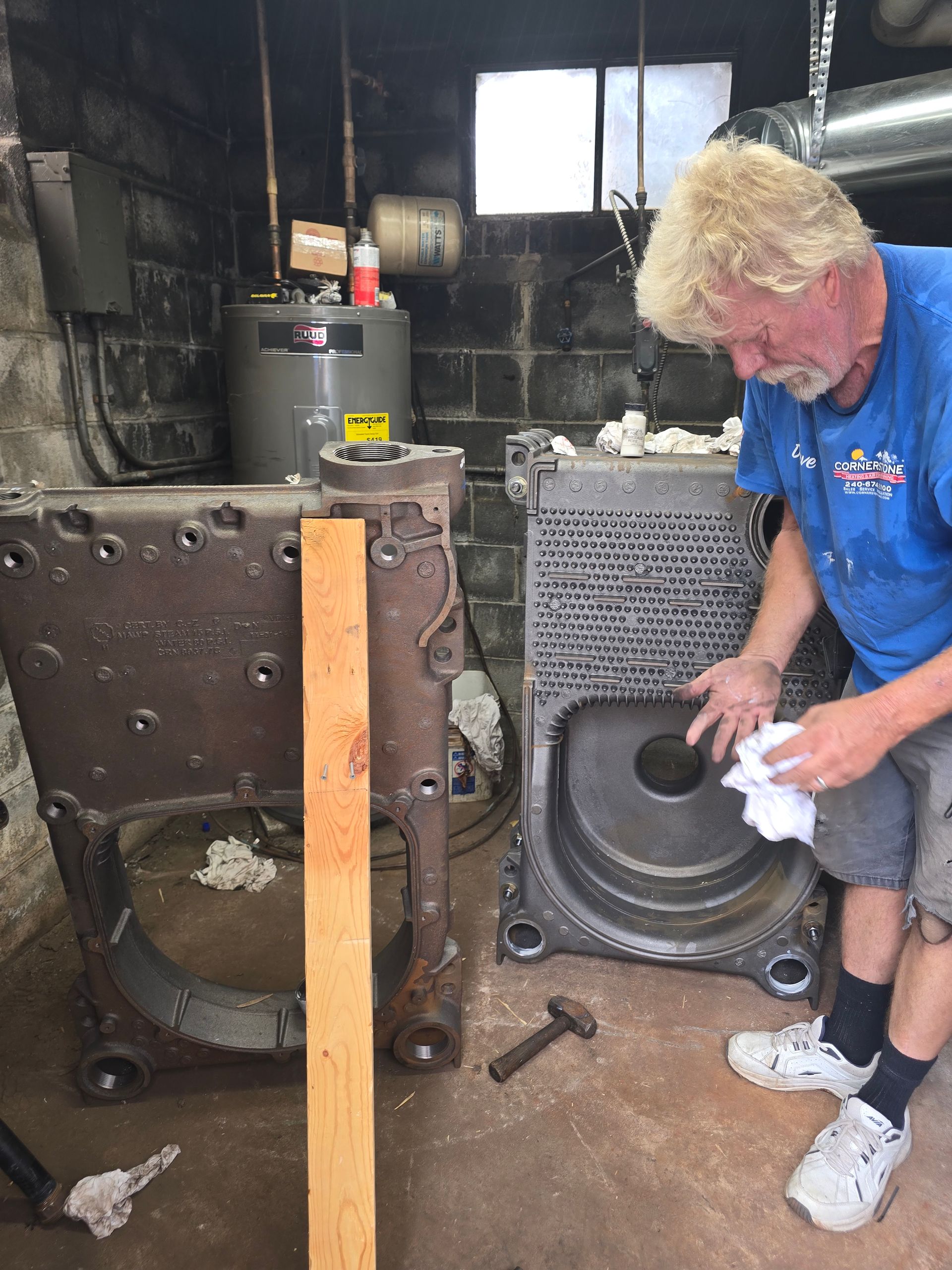Person cleaning a large speaker cabinet in a cluttered workshop or garage.