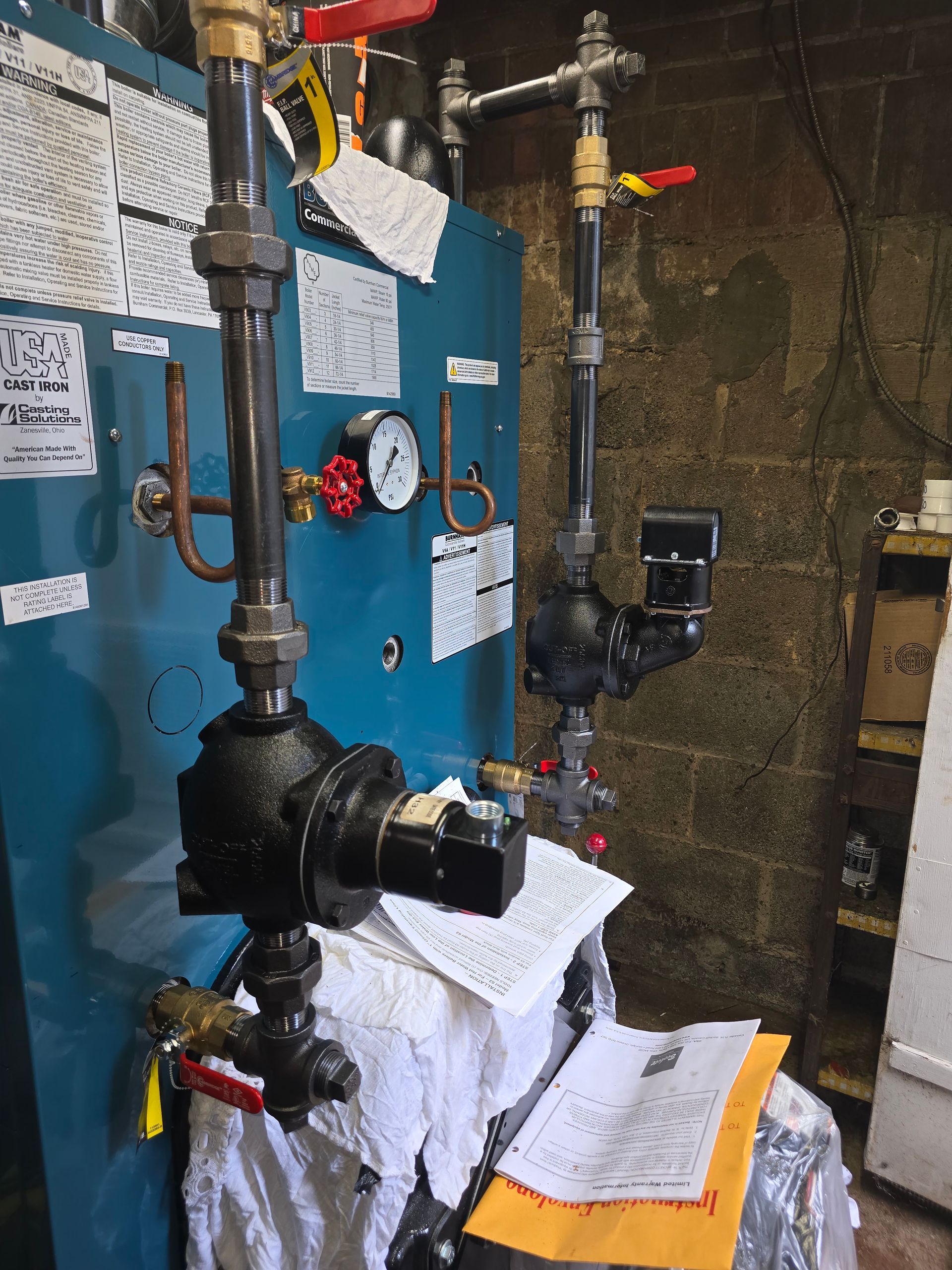 Blue industrial boiler with pipes, valves, and gauges in a utility room