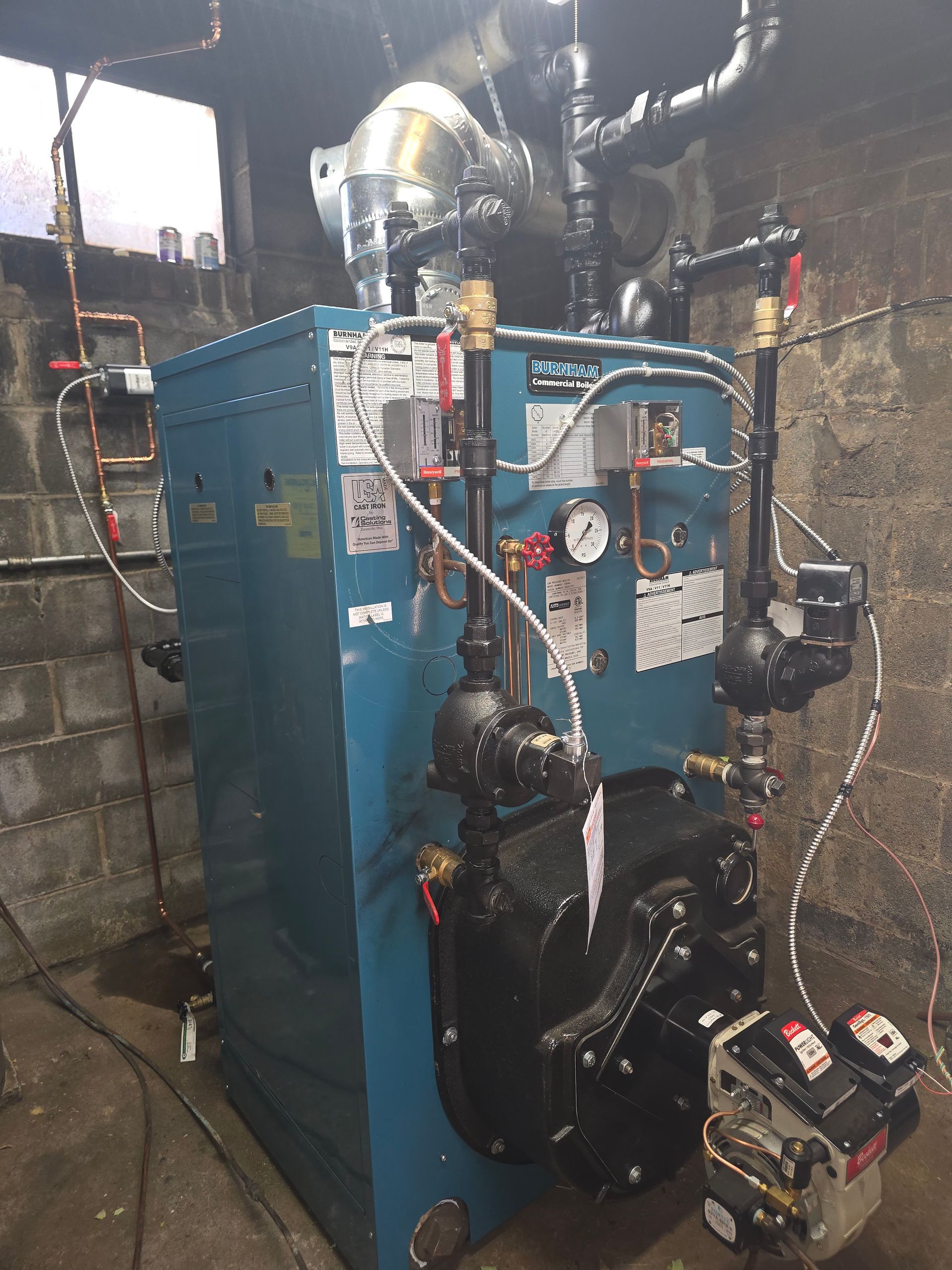 Blue boiler system with pipes, gauges, and pumps in a basement utility room