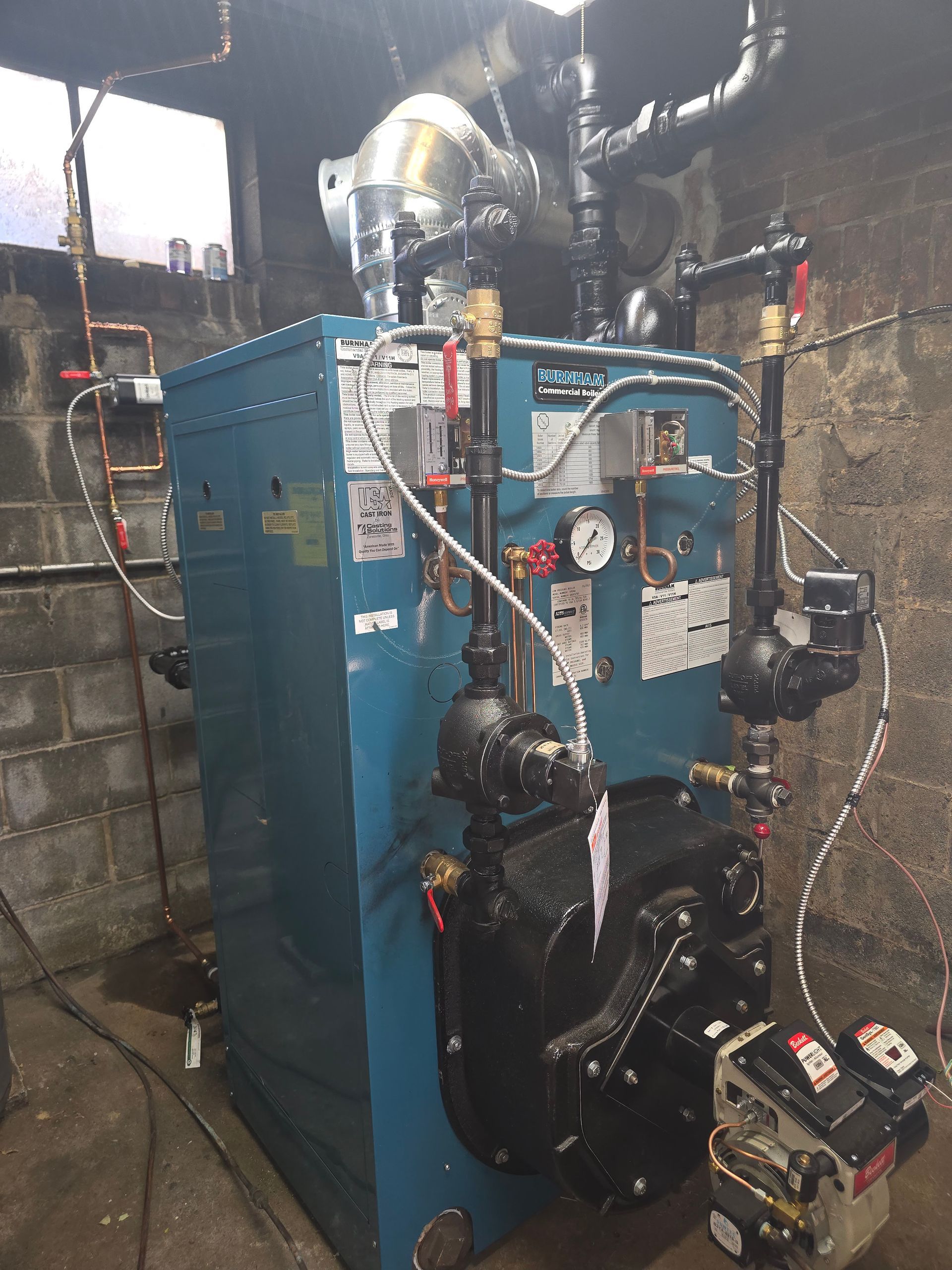 Blue industrial boiler with gauges, pipes, and vents in a utility room