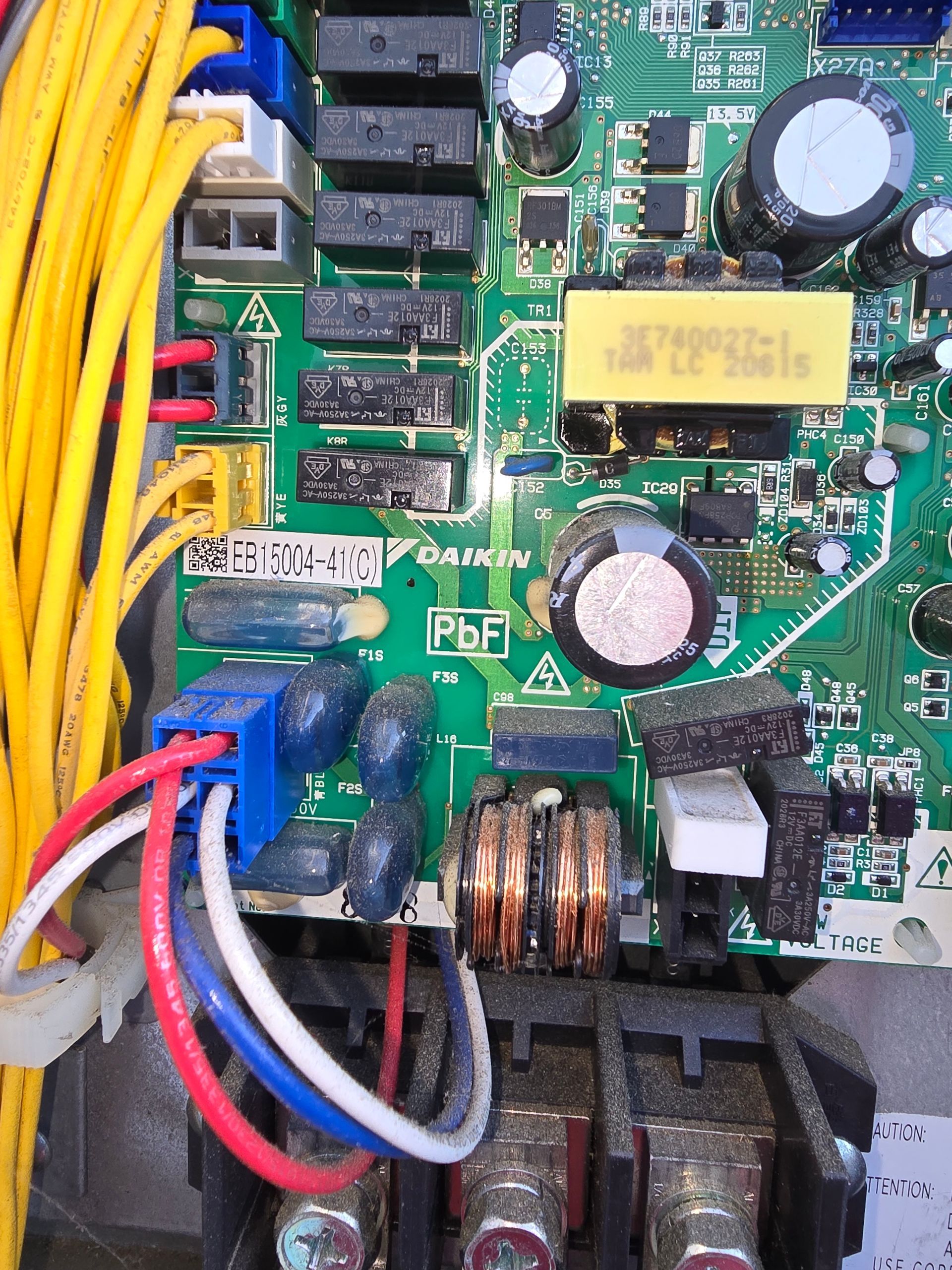 Close-up of a circuit board with yellow wires, capacitors, and soldered components