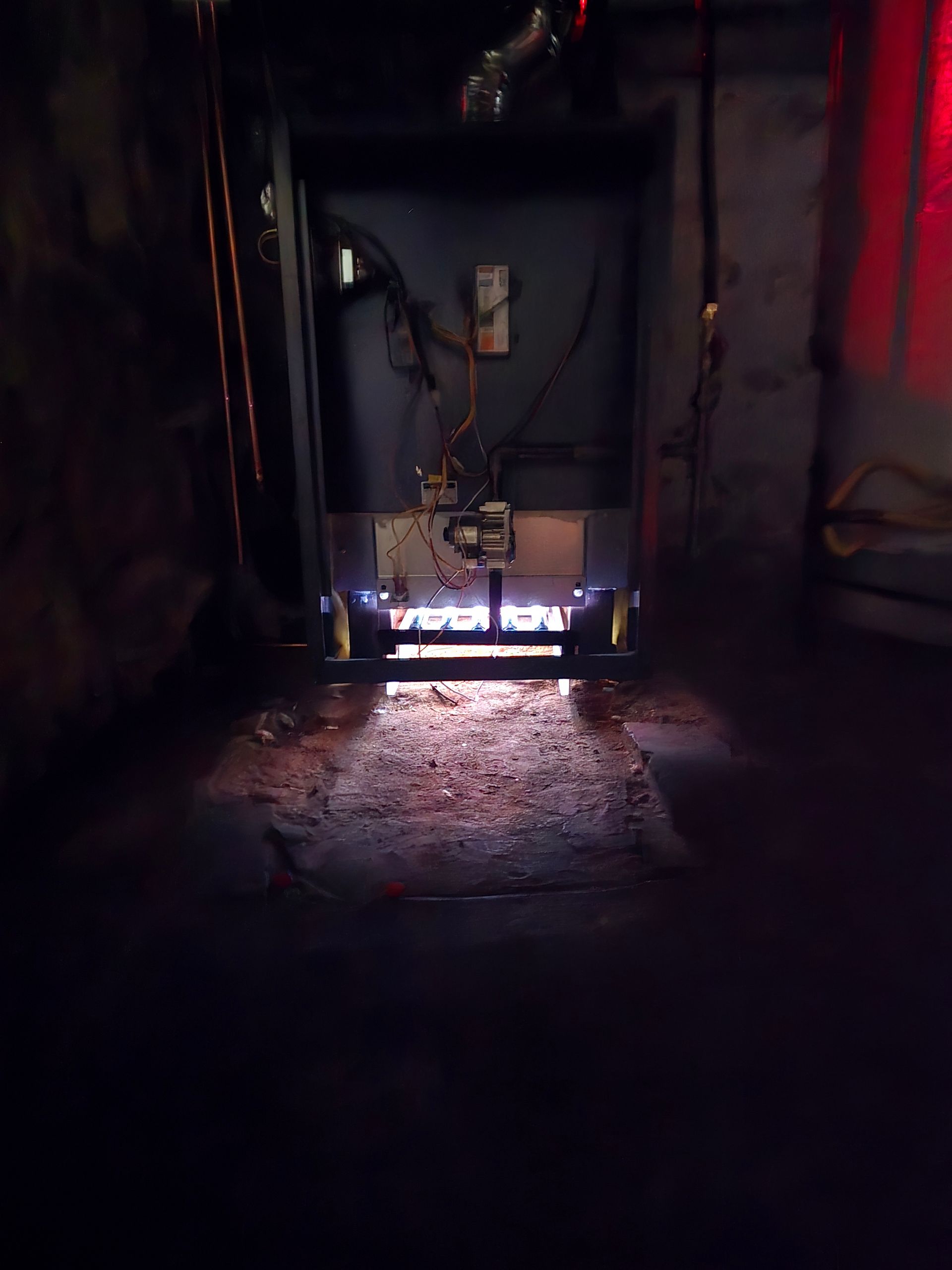 Dim industrial machine in a dark room, lit by a bright white strip at the base.