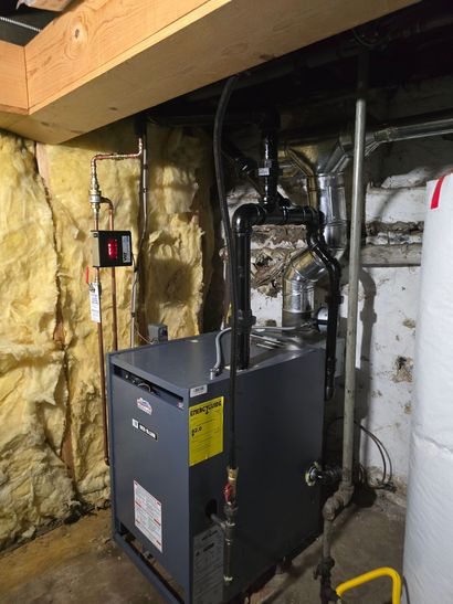Basement furnace and ductwork beside insulated wall and exposed wooden beam