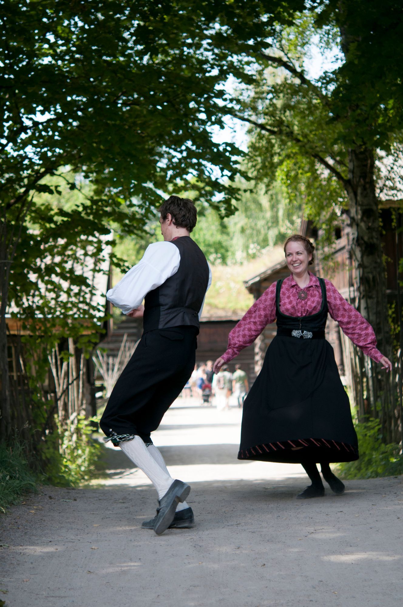 Folkedansere danser ute i friluftsmuseet på Norsk Folkemuseum.