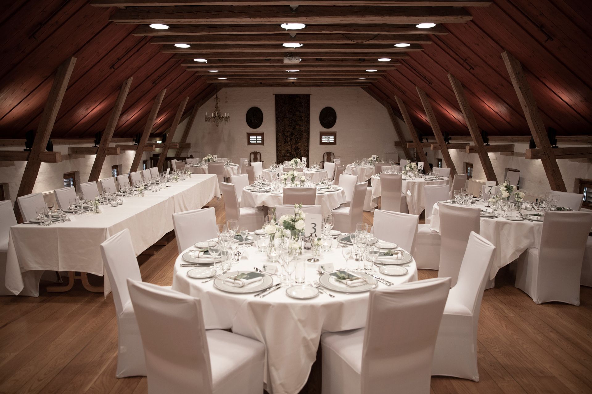 Elegant selskapssal med runde bord, hvite duker.