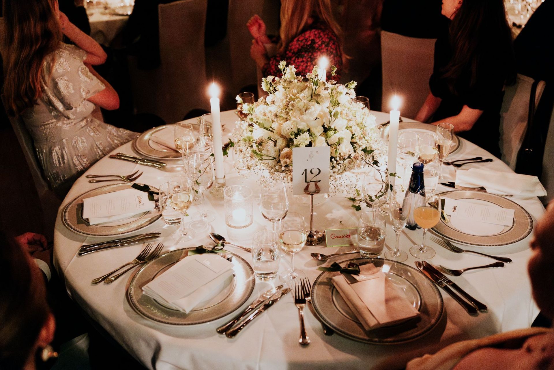 Elegant middagsbord med hvit duk og blomsterdekorasjon