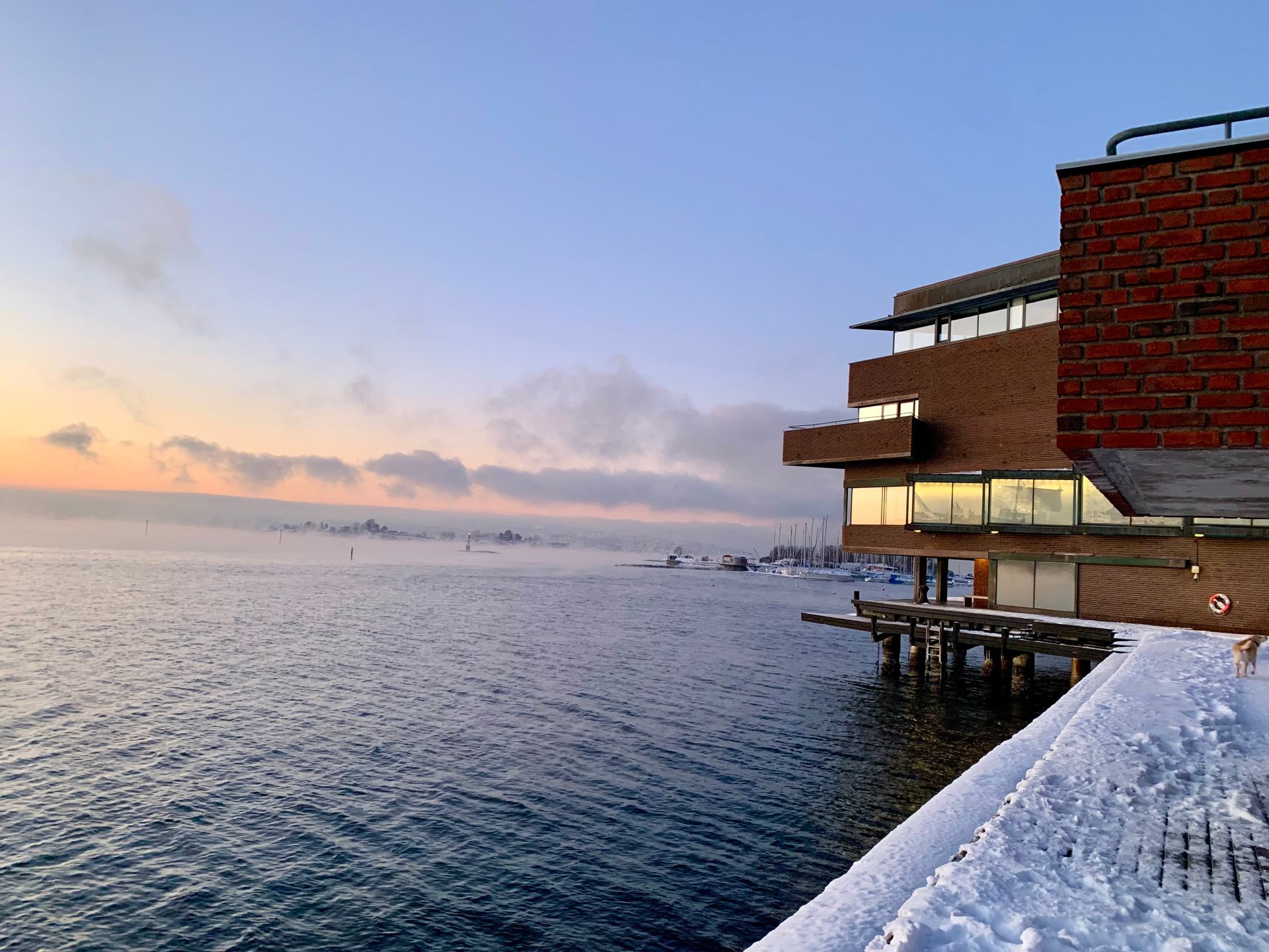 Snøhvit havnefront ved solnedgang ved siden av en murbygning og rolig havvann