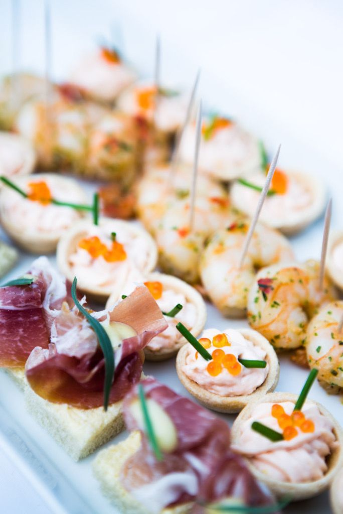 Assorterte småretter med kremtopping, prosciutto og gressløk på et serveringsbrett