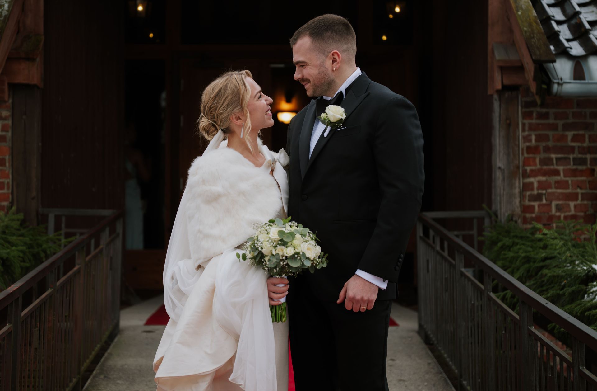 Smiling bride and groom on a chapel walkway.