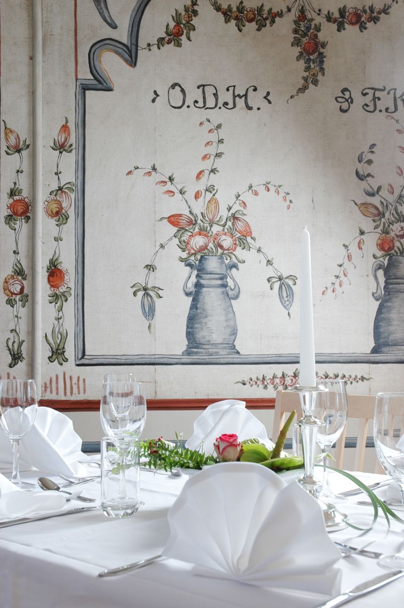 Elegant spisebord med hvite servietter, glass, blomster og stearinlys